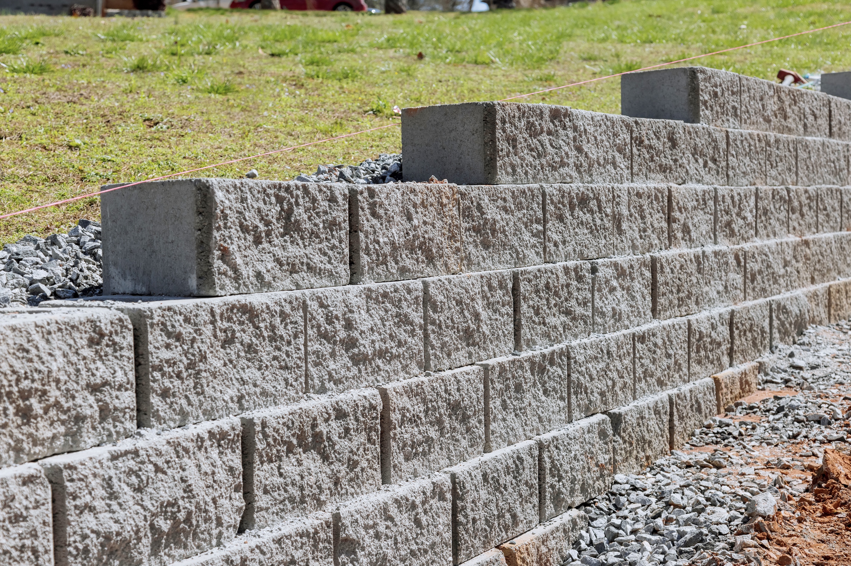 Engineered concrete block retaining wall under construction with proper gravel drainage backfill, on a Roseburg property.