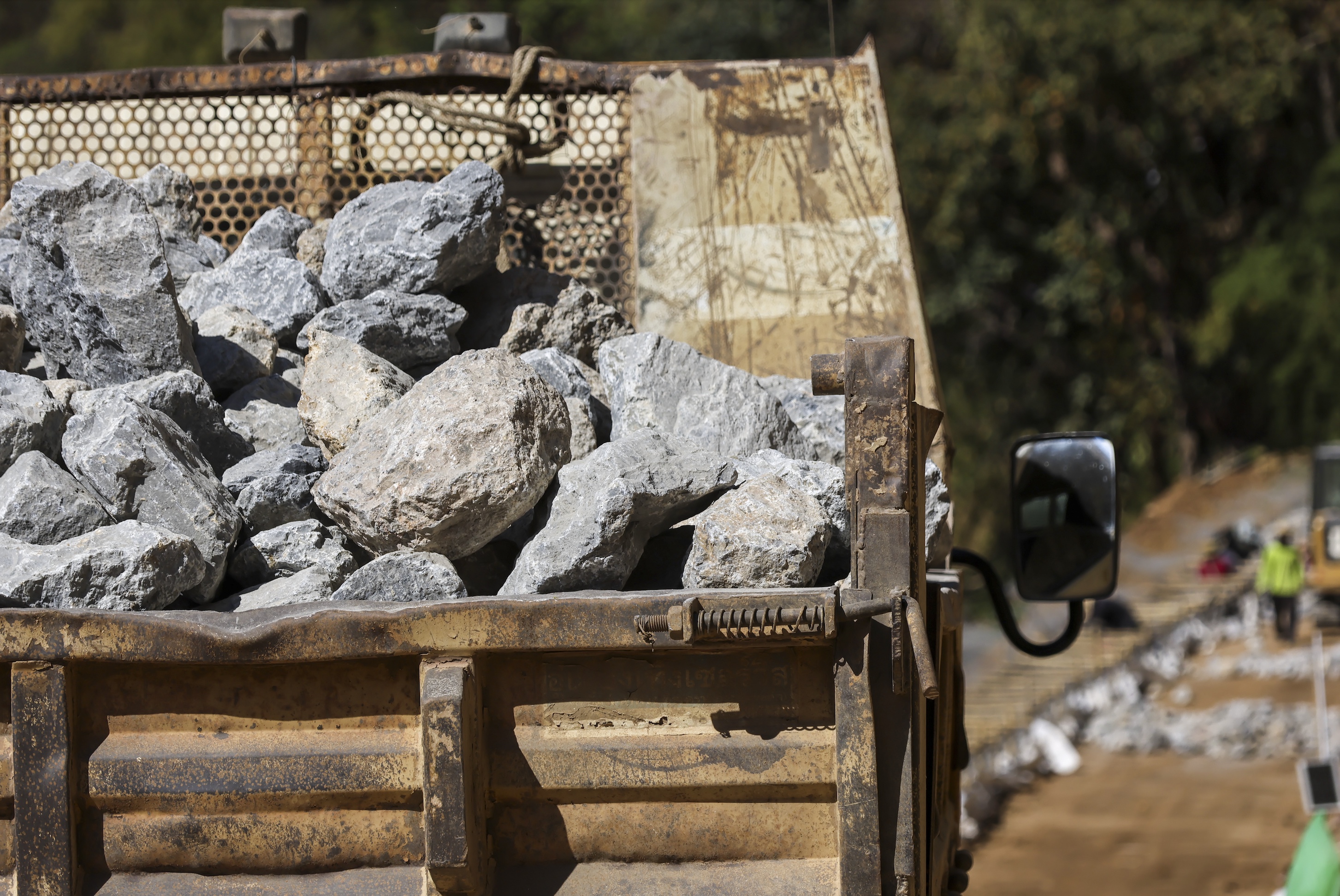 Dump truck bed full of large crushed rock at a job site, ready to be delivered.